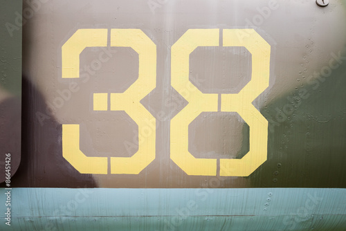 Number on a military aircraft fuselage. Texture. Old camouflage surface with exfoliated paint and rivets on a military aircraft.