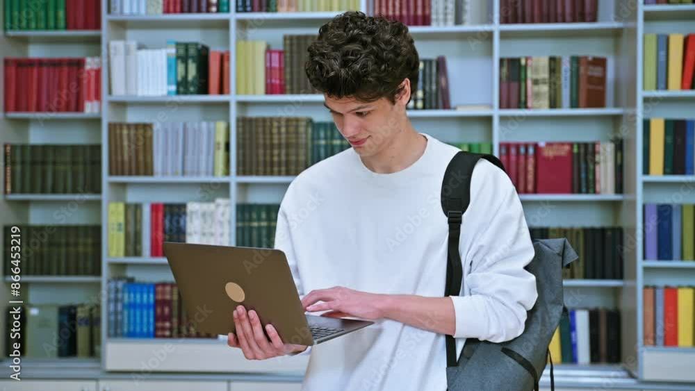 Portrait of handsome young male student with laptop in educational building in library Portrait of handsome young male student with laptop in educational building in library