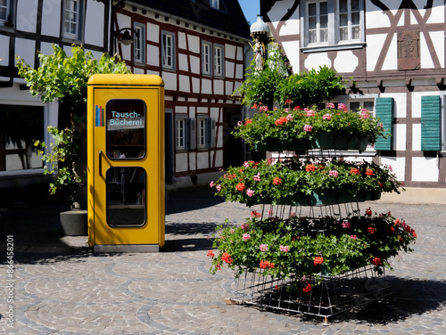 A public bookcase in an old yellow telephone booth.  photo