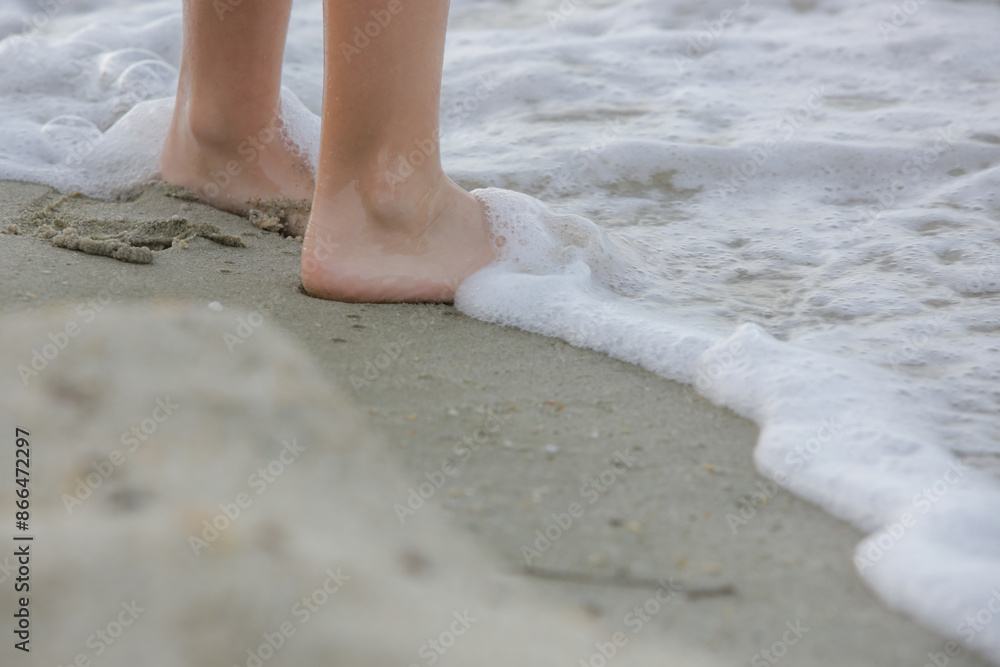 Barefoot child on sandy beach under seafoam. Barefoot child on sandy beach under seafoam.