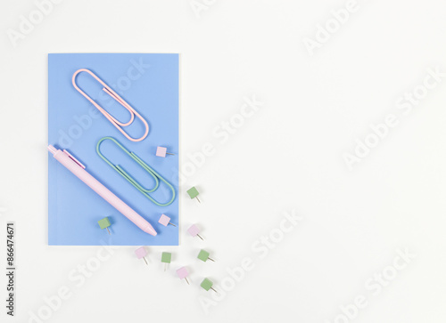 Top view of blue notebook on white background. Paperclips, pen and pins. School, office wallpaper. Flat lay, copy space. © STUDIA818
