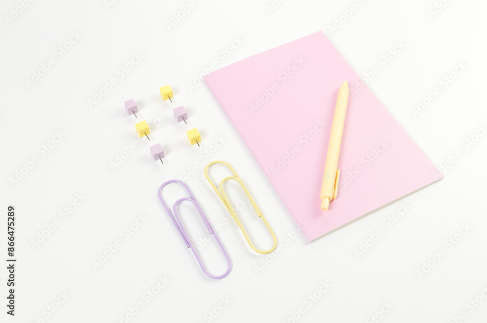 Top view of pink notebook on white background. Paperclips, pen and pins. School, office wallpaper. Flat lay, copy space. Top view of pink notebook on white background. Paperclips, pen and pins. School, office wallpaper. Flat lay, copy space.