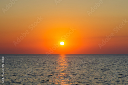 Sunset over the sea and sky. Sunrise ocean beach concept. Sunset over the sea with oranges and the sun in nature. Sunset with oranges and sun against a blue sky lifestyle in nature.