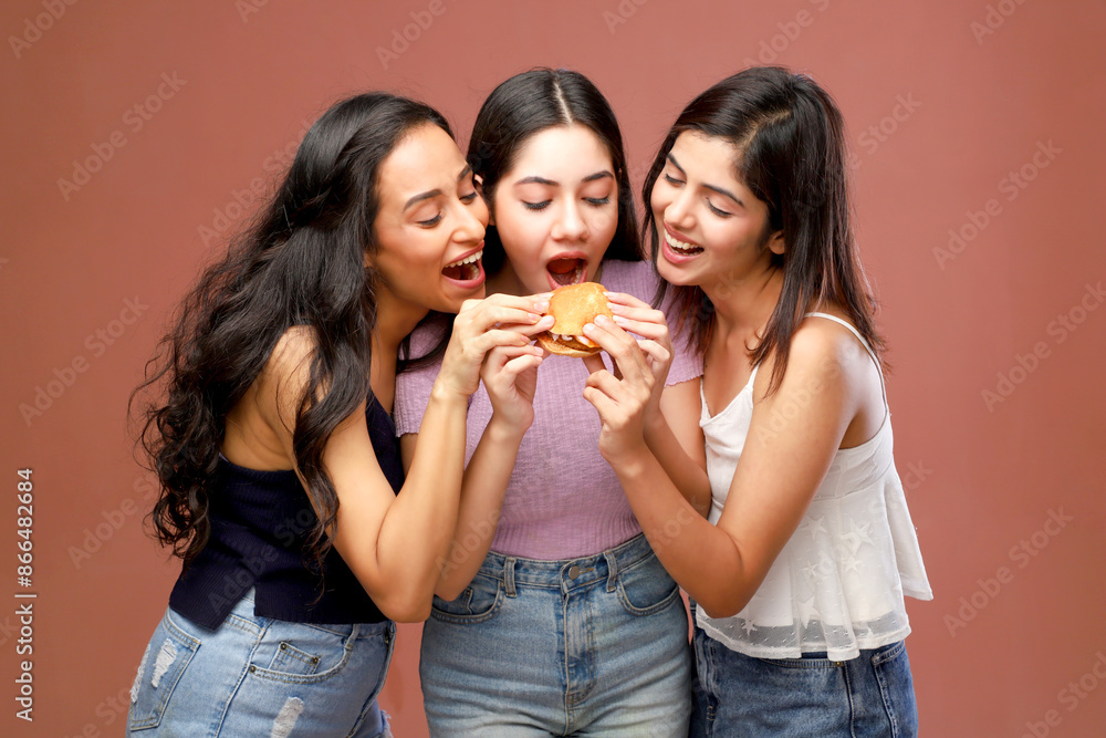 Three Women In Casual Outfits Having Fun And Eating A Burger Three Women In Casual Outfits Having Fun And Eating A Burger
