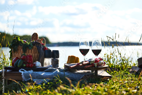 Background on a tray on the river bank in summer on a picnic with vegetables, kebab and glasses of red wine