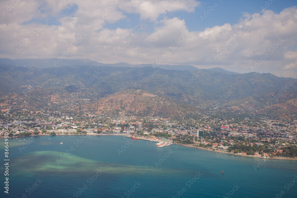 Fototapeta premium Aerial view of Dili City, the capital of Timor Leste. Urban settlements with a beach in the foreground and hills in the background.