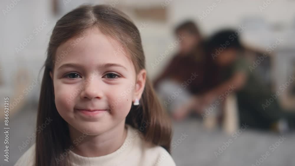 Close-up portrait of pretty young Caucasian girl sitting on floor, smiling sweetly and posing for camera while spending time at daycare centre Close-up portrait of pretty young Caucasian girl sitting on floor, smiling sweetly and posing for camera while spending time at daycare centre
