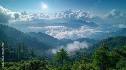 A beautiful view of a mountain range from above. The sky is blue and the sun is shining. The mountains are covered in lush green trees. © easybanana
