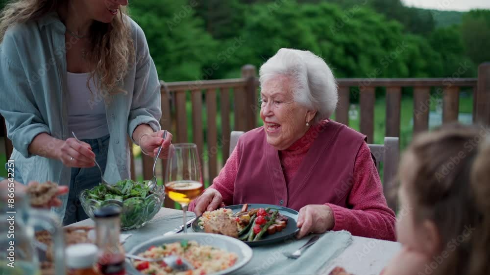 Multigenerational family sitting at big dining table, enjoying grilled food. Family barbecue in backyard, spending quality time outdoors together. Multigenerational family sitting at big dining table, enjoying grilled food. Family barbecue in backyard, spending quality time outdoors together.