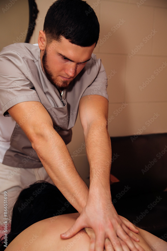 A male massage therapist does a professional massage in the salon. Massage of the back, neck, shoulders. Cosmetic care, alternative medicine. A male massage therapist does a professional massage in the salon. Massage of the back, neck, shoulders. Cosmetic care, alternative medicine.