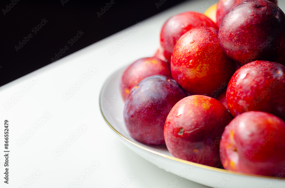 A white plate with a bunch of red plums on it A white plate with a bunch of red plums on it