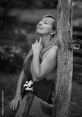 black and white portrait of a beautiful woman in sensual pose dreaming in a garden area © Barton
