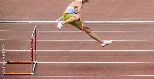 man athlete running 400-meter hurdles at summer athletics games photo