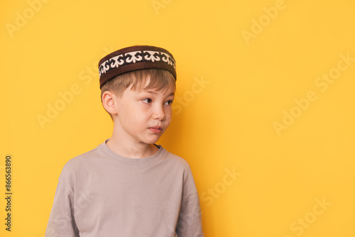 Bild auf Leinwand Boy in a Kazakh skullcap in front of a yellow background.