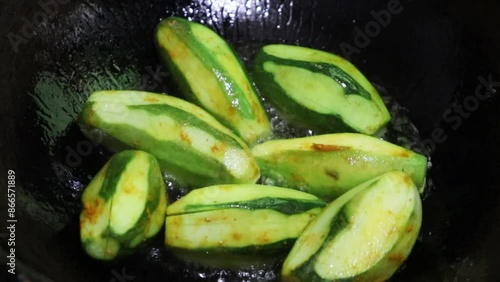 Close-up video of pointed gourd, parwal, parval (patol) frying in pan.4k. Pointed gourd potato curry, Indian food. 
 photo