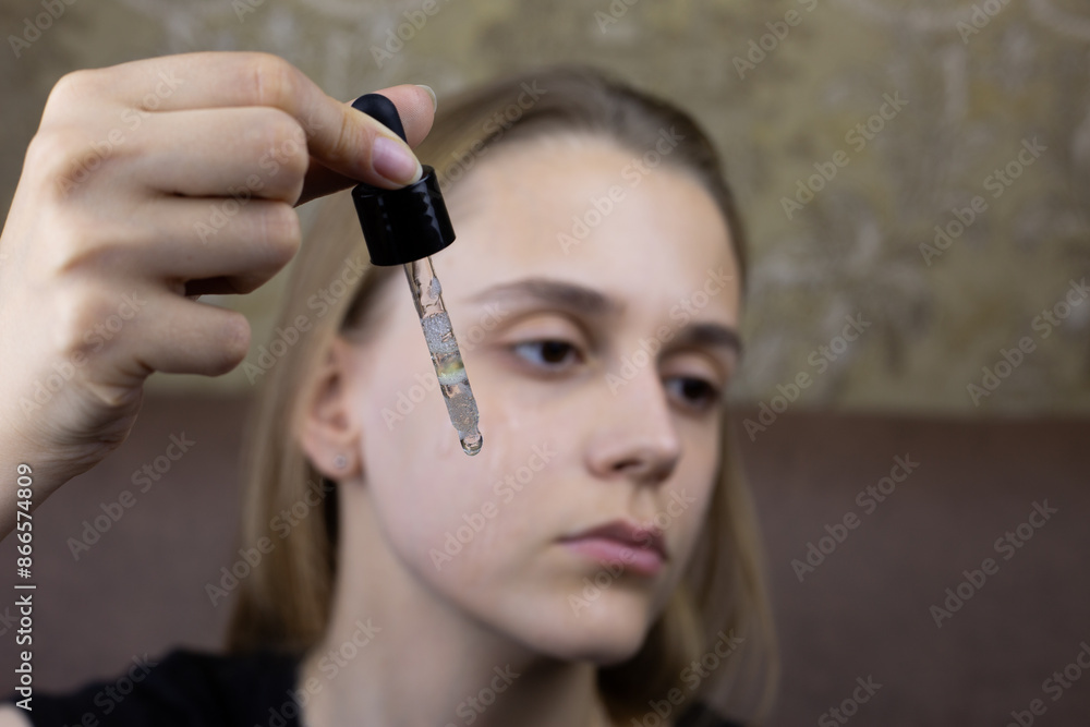 Pipette with oil for facial massage and moisturizing skin against the background of girl face Pipette with oil for facial massage and moisturizing skin against the background of girl face