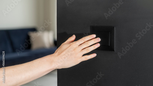 Cropped shot of woman hand pressing on light switch photo