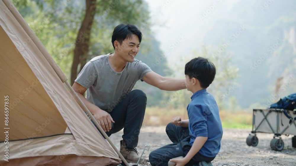 Little boy setting up camping tent together with his father Little boy setting up camping tent together with his father