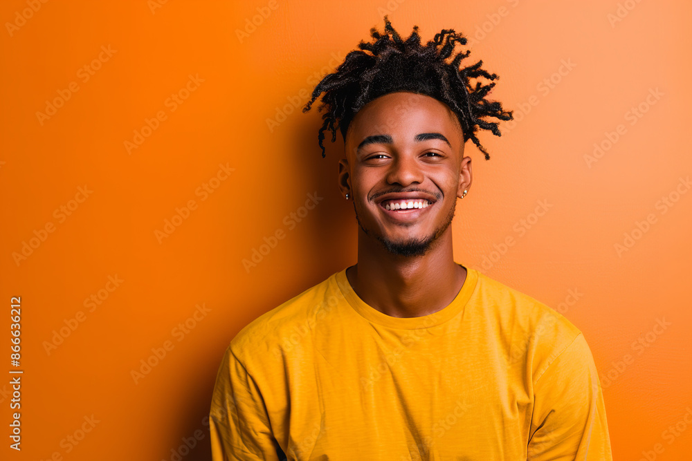 A good-looking young man is captured in a casual studio shot, smiling happily against a vibrant color background A good-looking young man is captured in a casual studio shot, smiling happily against a vibrant color background