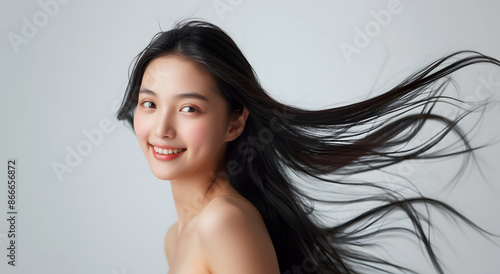 A young woman with a bright smile and beautiful, flowing black hair. Ideal for advertising shampoo, conditioner and cosmetic products. This image emphasizes the beauty and elegance of nature.