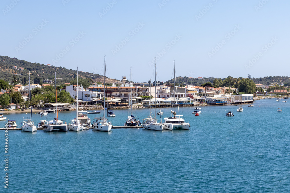 Skiathos, Greece A picturesque marina featuring boats docked by a tranquil coastal town, set against rolling hills under clear blue skies. Ideal for travel and tourism themes. Skiathos, Greece A picturesque marina featuring boats docked by a tranquil coastal town, set against rolling hills under clear blue skies. Ideal for travel and tourism themes.