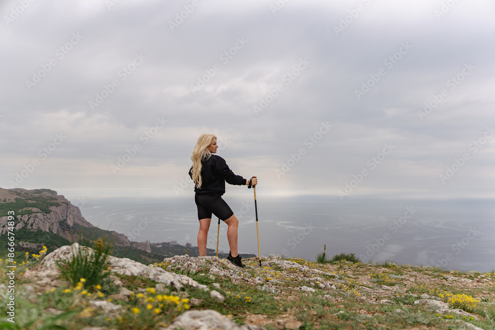 Obraz premium A woman stands on a hill overlooking the ocean