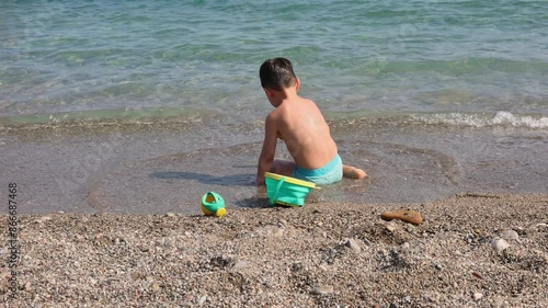 kid playing on beach in sea water swimming,splashing,running or floating on waves.child with sun cap or diving snorkel mask.preschooler boy playing with boat ship toy,digging with plastic shovel.