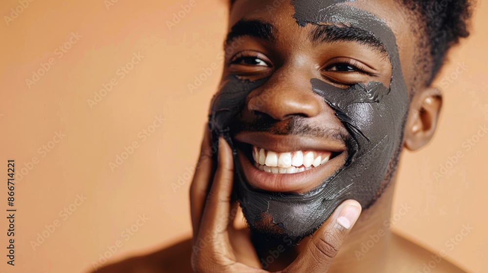 An African American man with a clay mask, smiling and touching his face, indicating a self-care moment An African American man with a clay mask, smiling and touching his face, indicating a self-care moment