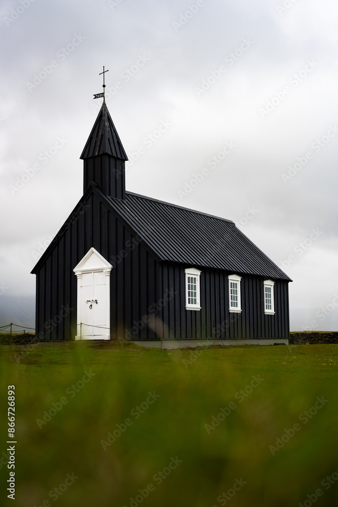 Fototapeta premium Stunning view of the black church of Budir with defocused grass in the foreground. Búðakirkja is a small wooden church located on the south side of Snæfellsnes, Iceland..