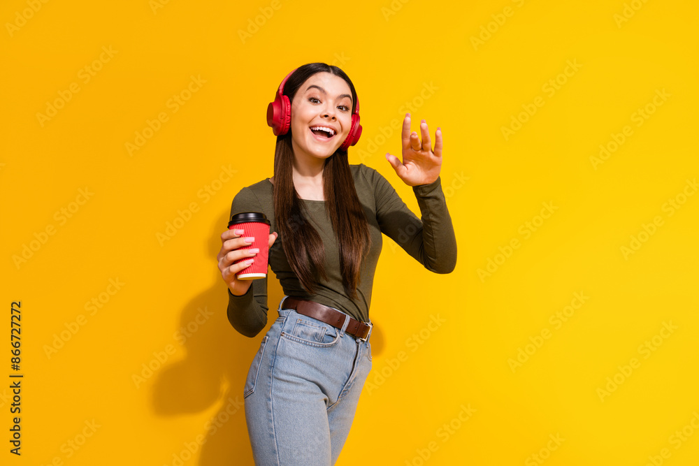 Photo portrait of lovely teen lady headphones coffee dance dressed stylish khaki garment isolated on yellow color background Photo portrait of lovely teen lady headphones coffee dance dressed stylish khaki garment isolated on yellow color background