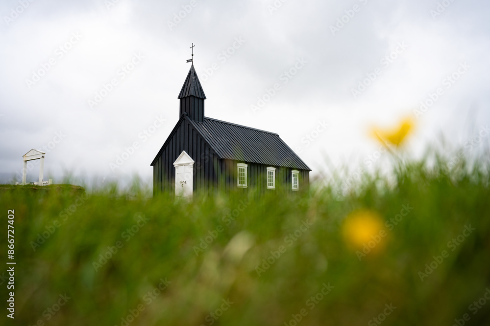 Stunning view of the black church of Budir with defocused grass in the foreground. Búðakirkja is a small wooden church located on the south side of Snæfellsnes, Iceland..