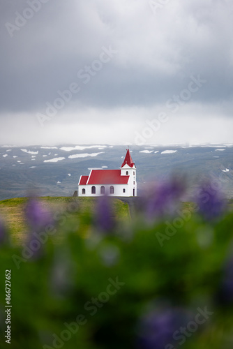 Obraz na płótnie Stunning view of the Ingjaldshólskirkja, a historic little red-roofed church located in Snæfellsnes penisula, A nice road leads down and back up a hill with great views of the mountains. w salonie