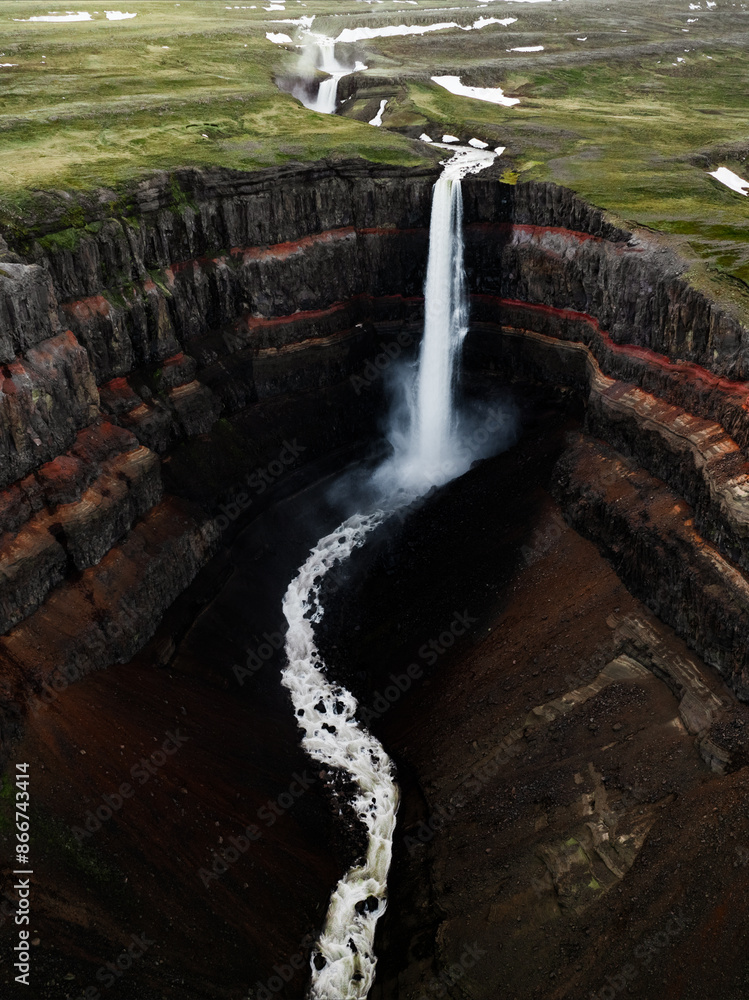 View from above, stunning aerial view of the Hengifoss Waterfall. Hengifoss, is eye-catching due to the striking red clay and black basalt patterns of the cliff face. Fljótsdalshreppur, East Iceland.