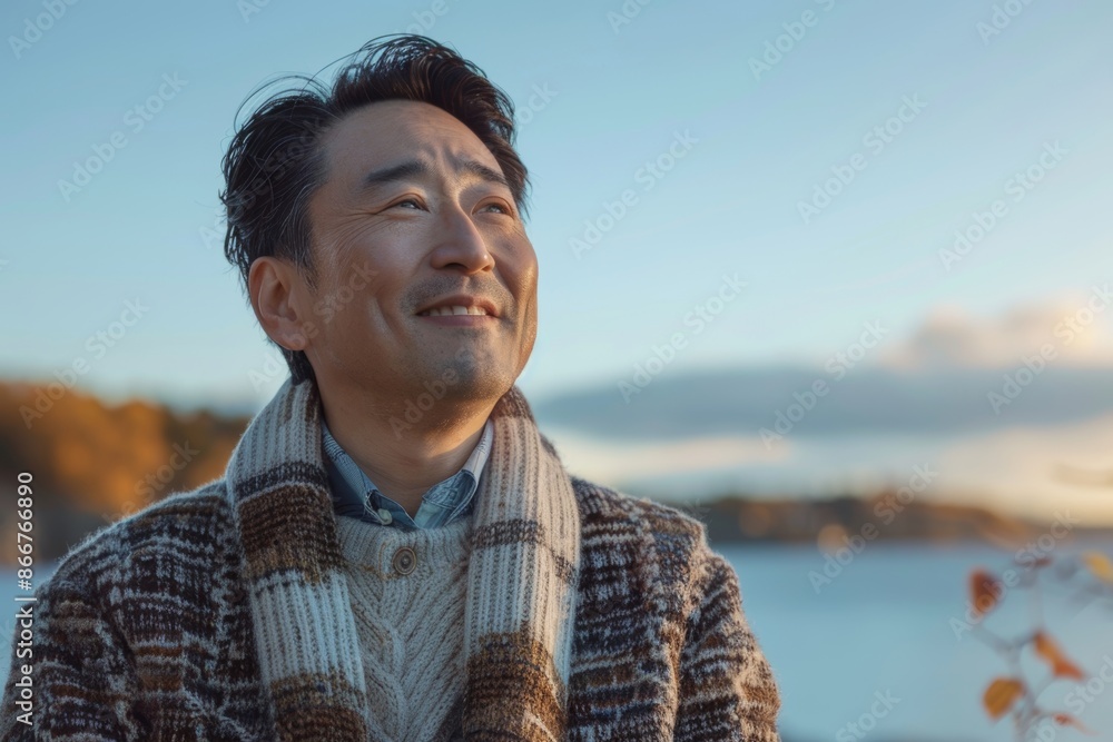 Portrait of a happy asian man in his 40s wearing a chic cardigan over serene lakeside view Portrait of a happy asian man in his 40s wearing a chic cardigan over serene lakeside view