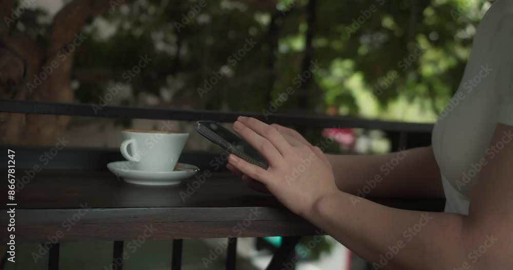 Girl at the terrace of a cafe using a smartphone. Young woman using smart phone surfing social media, checking news, playing mobile games or texting messages sitting of cafe. 4K Girl at the terrace of a cafe using a smartphone. Young woman using smart phone surfing social media, checking news, playing mobile games or texting messages sitting of cafe. 4K