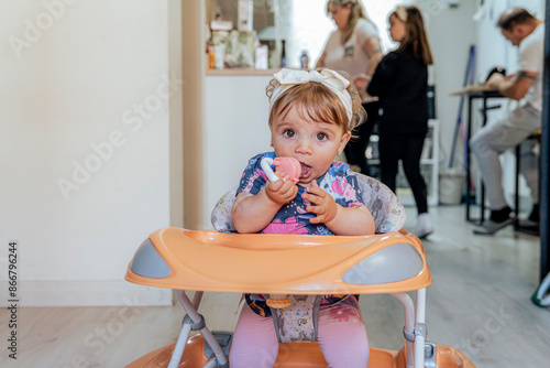 Toddler enjoys a meal in highchair while family is busy in the background