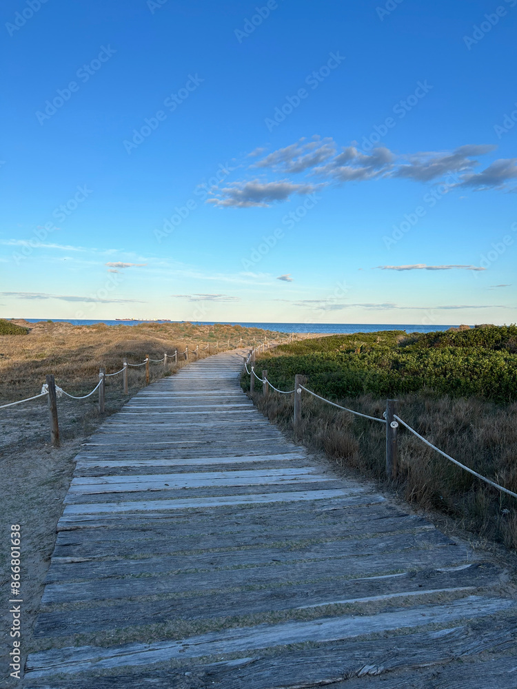 Fototapeta premium road made of wooden planks leading to the sea on a sunny day in Spain, path to the sea