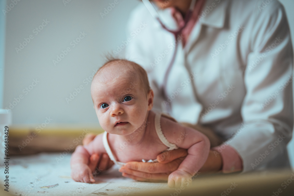 Fototapeta premium A caucasian female pediatrician performs a checkup on an alert newborn baby lying on a hospital table, ensuring routine health measures are in place with her medical expertise.