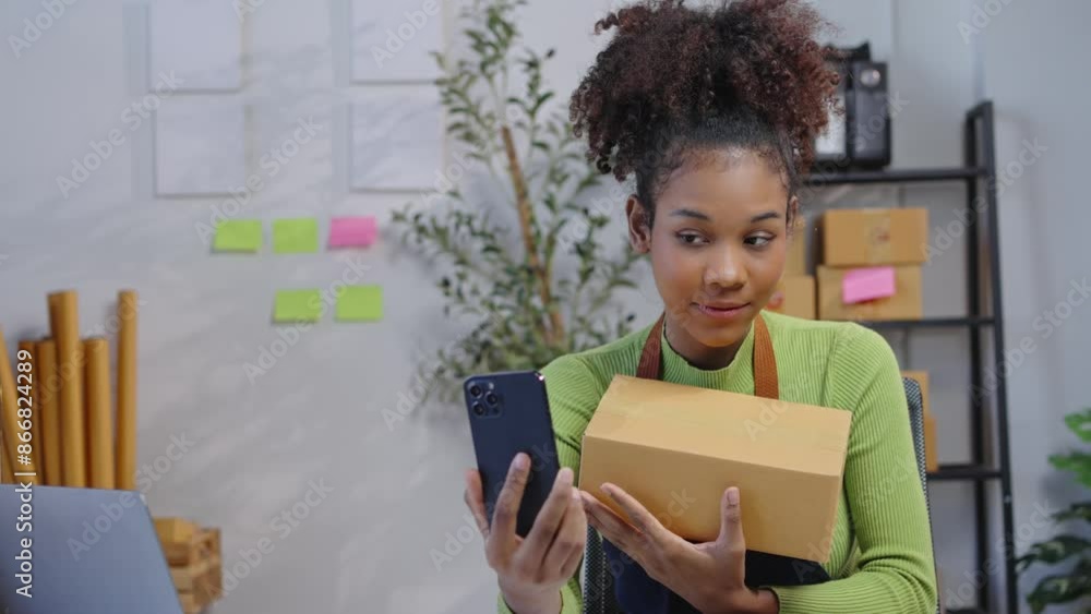Young female entrepreneur unboxes and showcases a product during a slow-motion video call in a home office setting Young female entrepreneur unboxes and showcases a product during a slow-motion video call in a home office setting