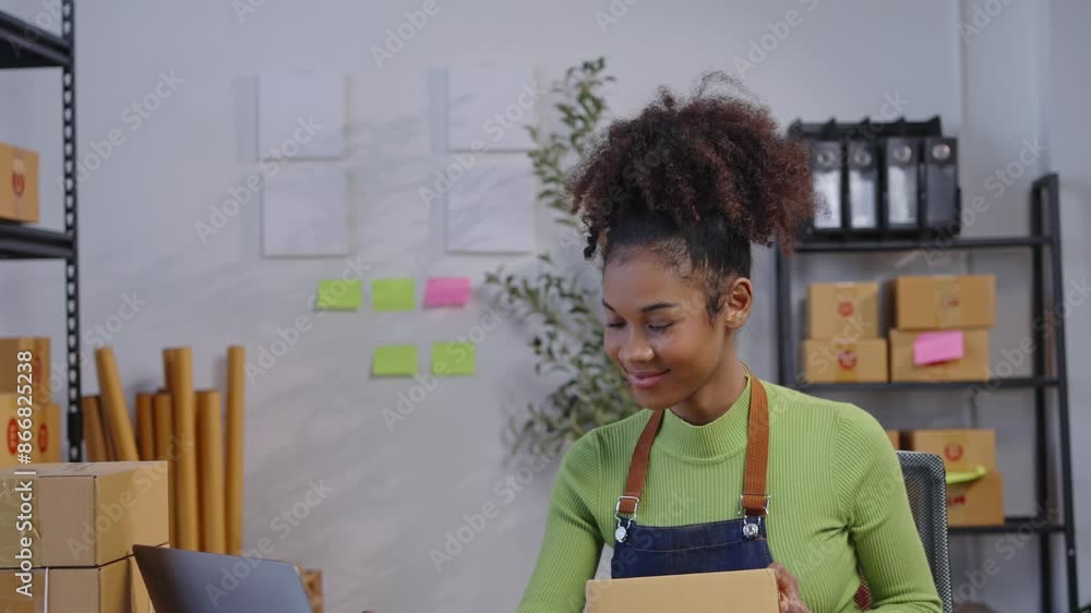 Businesswoman packages products and uses a laptop in a warehouse office, surrounded by shipping boxes and office supplies. Perfect for showcasing entrepreneurship, small business, and ecommerce Businesswoman packages products and uses a laptop in a warehouse office, surrounded by shipping boxes and office supplies. Perfect for showcasing entrepreneurship, small business, and ecommerce