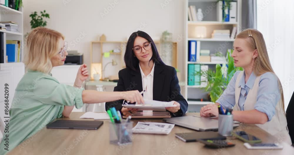 Female Office Workers Discuss Sales Reports Female Office Workers Discuss Sales Reports