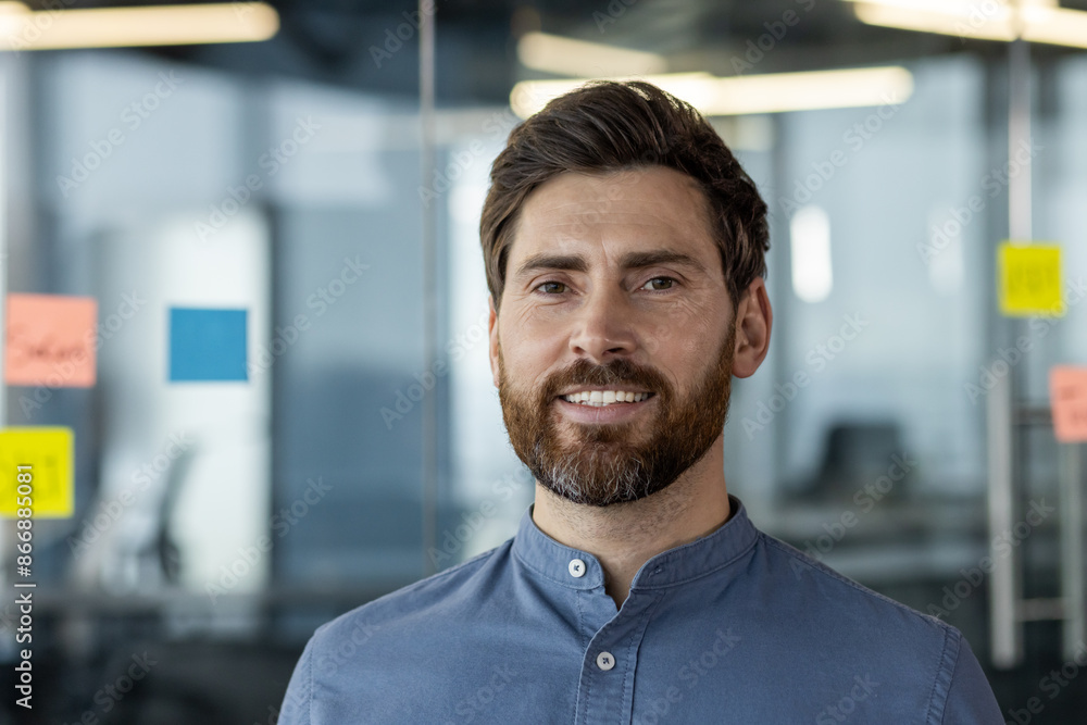 Naklejka premium Confident businessman with beard smiling in office setting with glass walls and sticky notes