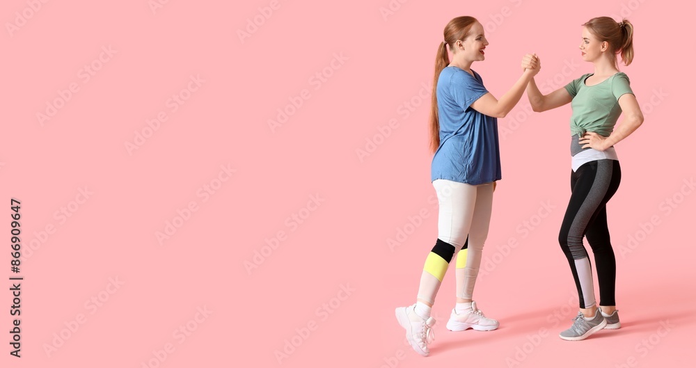 Obraz premium Portrait of sporty young women holding hands on pink background with space for text