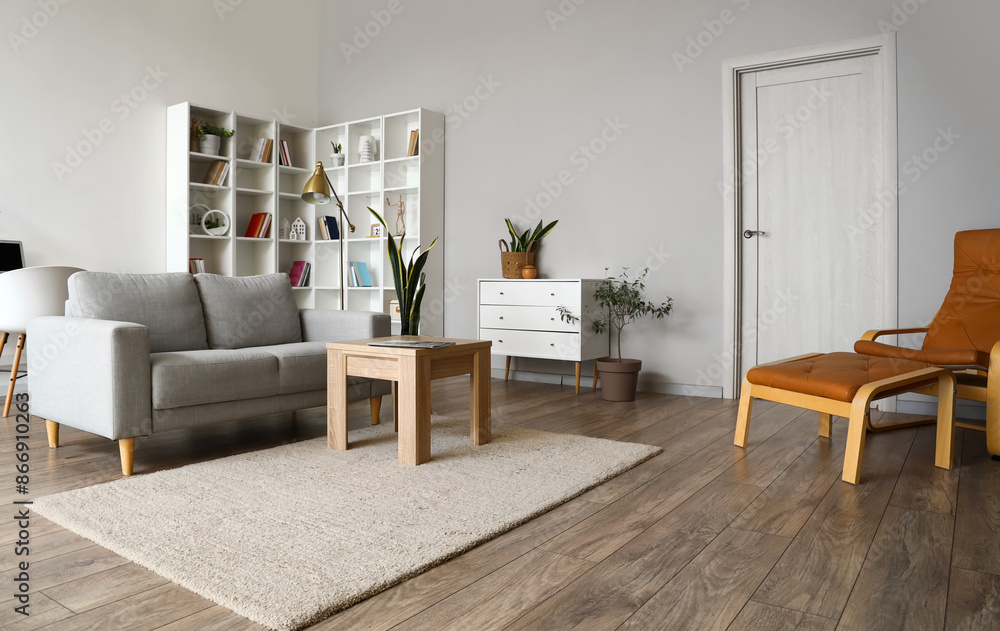 Interior of light living room with grey couch, table and shelving unit Interior of light living room with grey couch, table and shelving unit