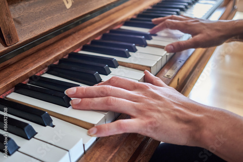Young woman's hands playing on an old piano, close-up