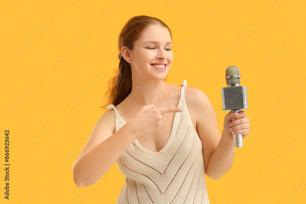 Beautiful young woman pointing at microphone on yellow background Beautiful young woman pointing at microphone on yellow background