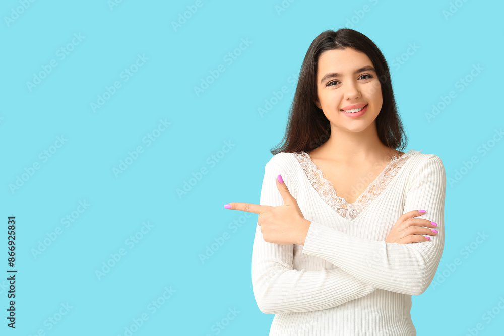 Young happy smiling woman pointing at something on blue background Young happy smiling woman pointing at something on blue background