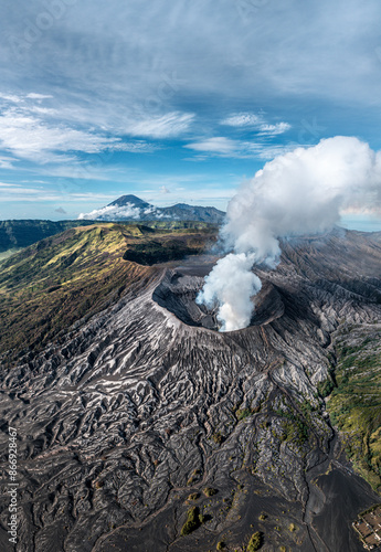 Aerial image of smoking mount Bromo volcano and surrounding caldera landscape during morning golden hour on East-Java, Indonesia