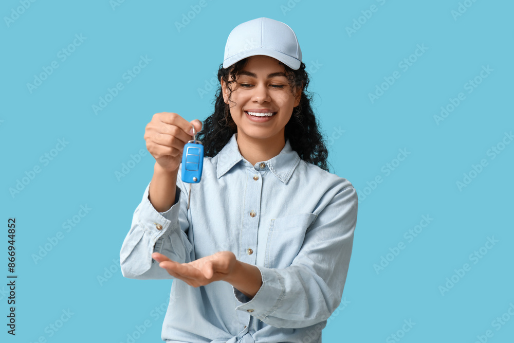 Beautiful young African-American woman with car key on blue background Beautiful young African-American woman with car key on blue background