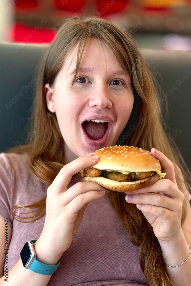 Hungry young woman eating fast food burger Hungry young woman eating fast food burger